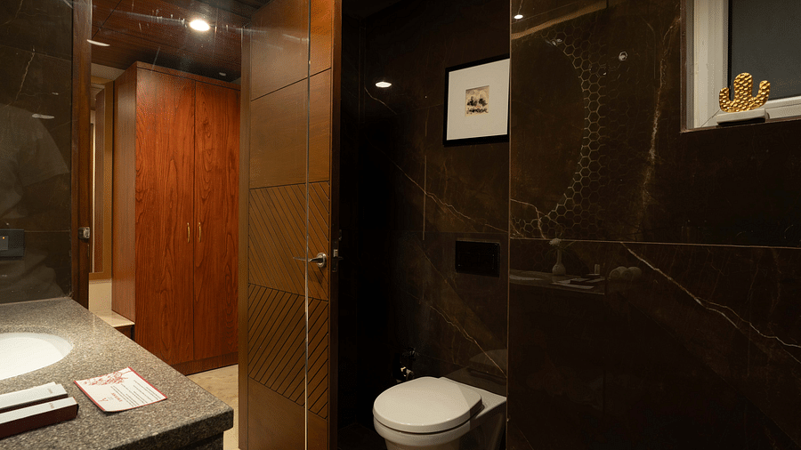 Transparent glass divider separating the showering and toilet areas in the Deluxe room's bathroom at Inde Signature Jaipur.