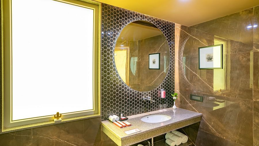Large circular mirror above the washbasin in the bathroom of the Suite at Inde Signature Jaipur.