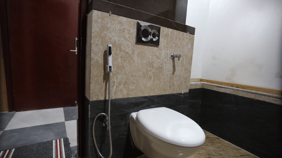 A bathroom at Indus Serinity, Leh Ladakh, featuring a toilet seat, a shooter, and a bin.