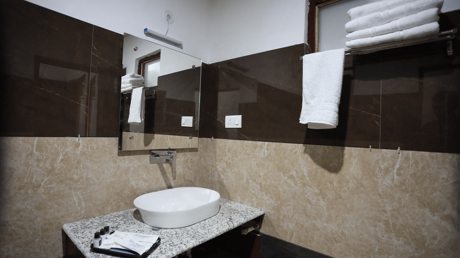 A bathroom at Indus Serinity, Leh Ladakh, featuring a sink, a mirror, and a hanging towel. 