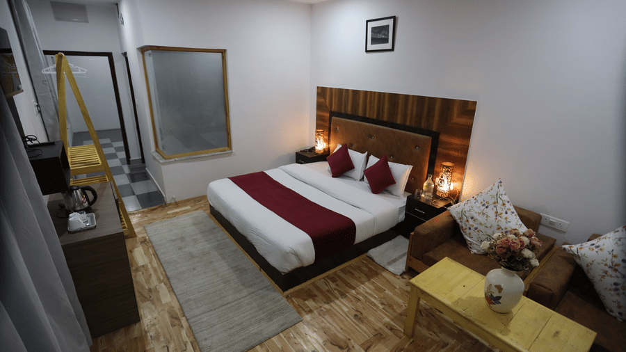 A room with a large bed, pillows, spreads, a television, a table, and wall arts. | Indus Serinity, Leh Ladakh