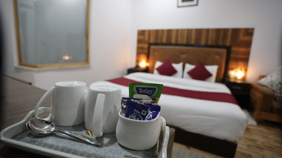 A room with a large bed, pillows, spreads, cups, and saucers placed on a plate | ndus Serinity, Leh Ladakh