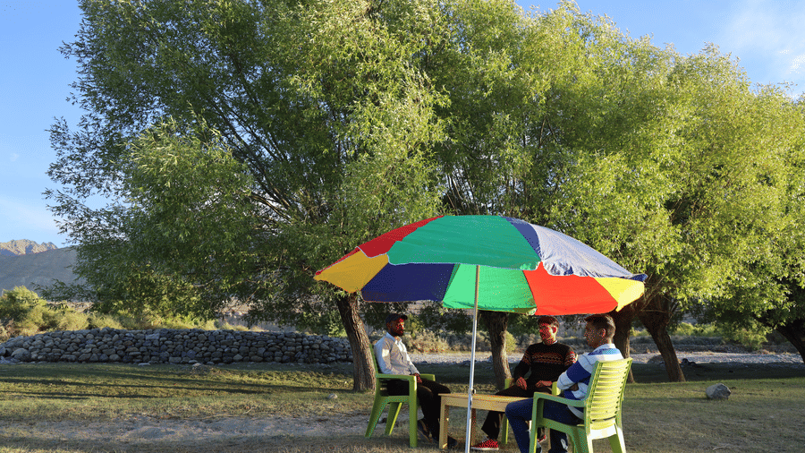 An outdoor seating with an umbrella covering the guests sitting under the sunlight. | Indus Serinity, Leh Ladakh
