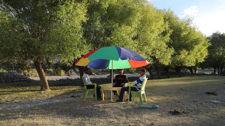 An outdoor seating with an umbrella covering the guests sitting under the sunlight. | Indus Serinity, Leh Ladakh
