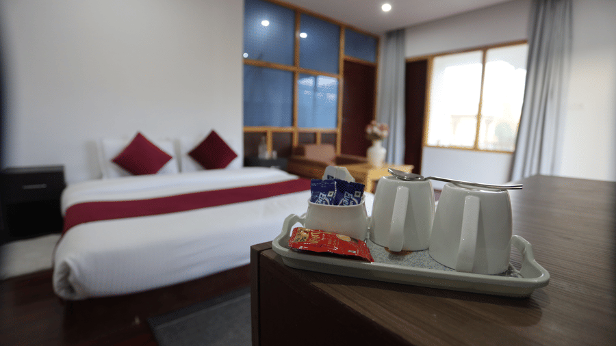 A room with a large bed, pillows, spreads, windows, and saucers. | Indus Serinity, Leh Ladakh