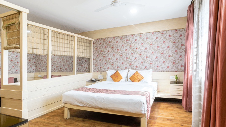 A room with white king size bed, floral wallpaper and wooden partition at Infiniti Hotel, Indore.