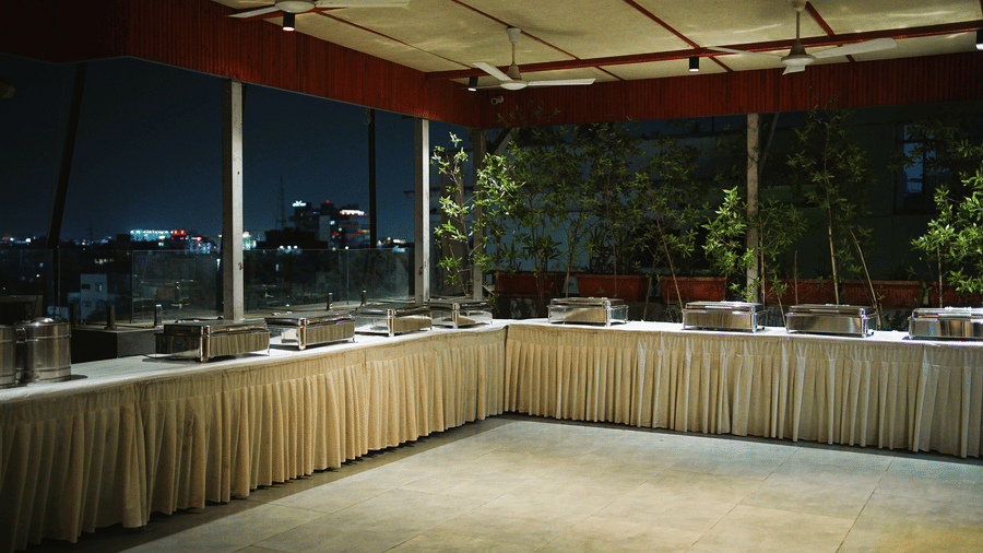 A dining space arranged in an event hall with food being kept on several plates. | Infiniti Hotel, Indore
