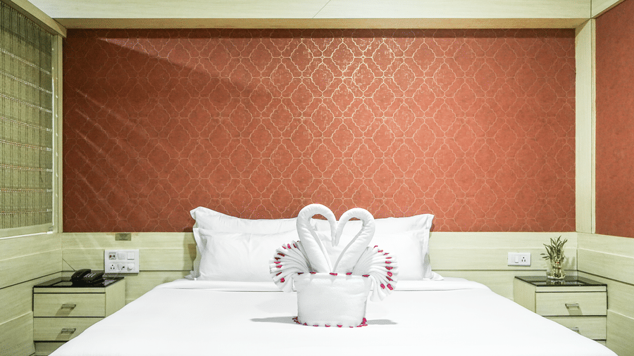 A room with a neatly made bed, featuring two swan-shaped towels at Infiniti Hotel, Indore.