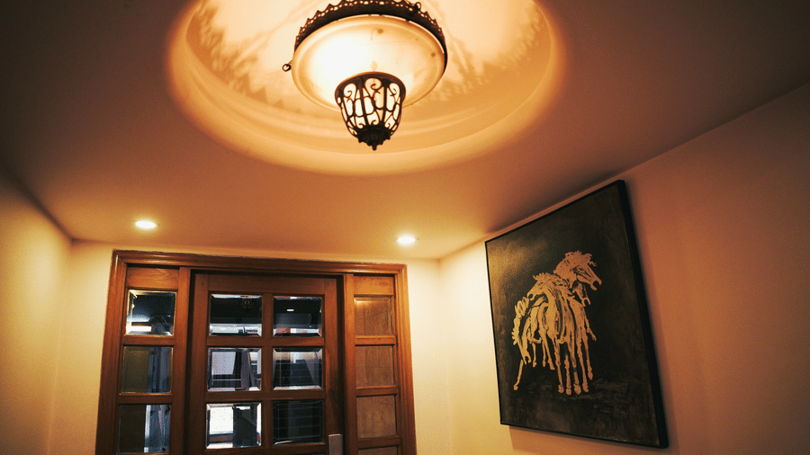 Infiniti Hotel, Indore | A chandelier lighting up to a wall art and windows.