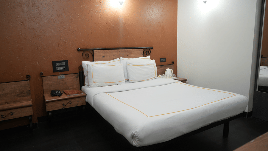 A bedroom at Infiniti Hotel, Indore featuring double bed, bedside tables, wall lamps, and telephone.