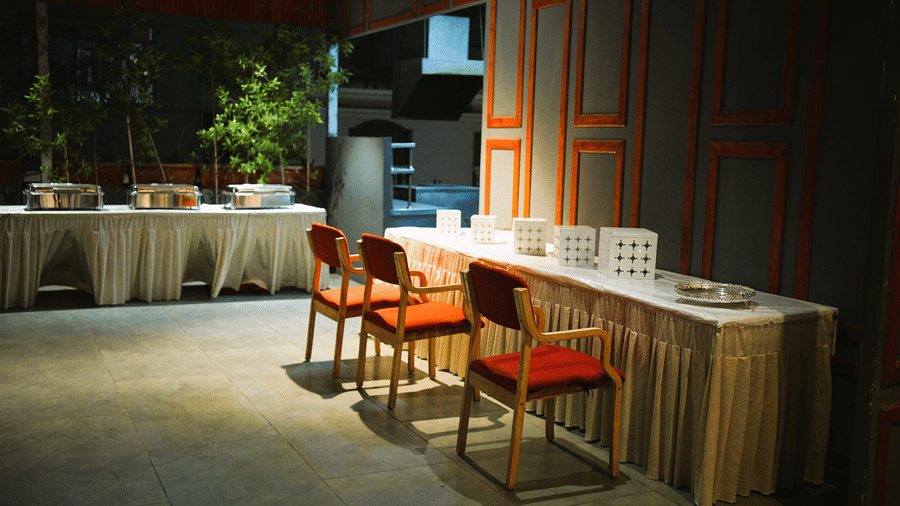 Infiniti Hotel, Indore | A banquet hall with chairs and tables with dishes placed on a table.