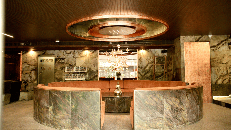 A circular lounge area at Infiniti Hotel, Indore featuring curved seating, central table, and hanging light fixture.