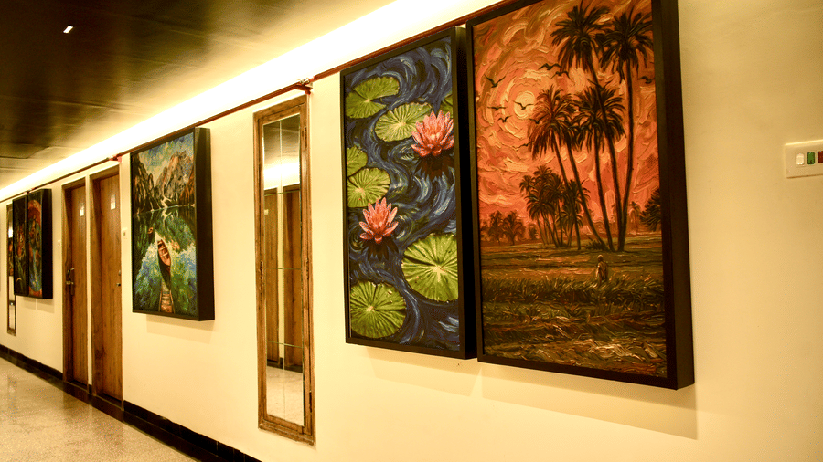 A corridor at Infiniti Hotel, Indore featuring framed paintings, mirror, and wooden doors along the wall.