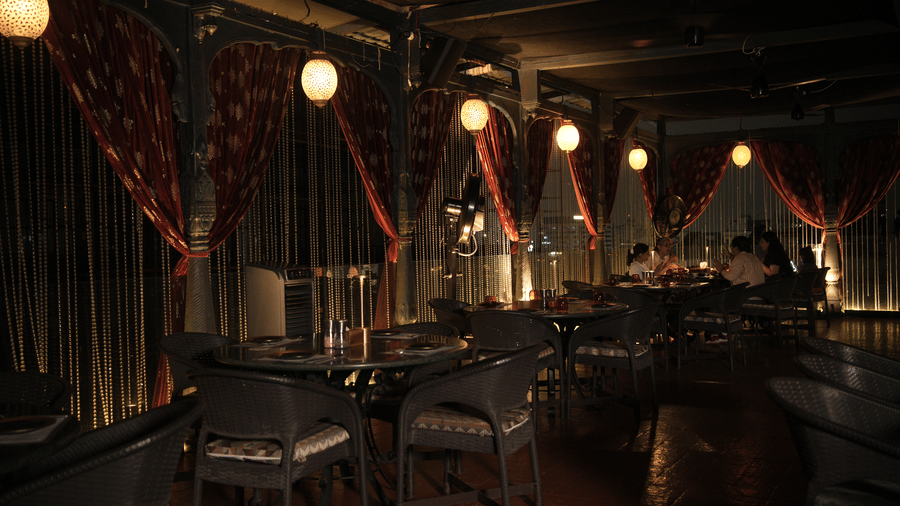 Infiniti Hotel, Indore | A dining space with lights, tables and chairs.