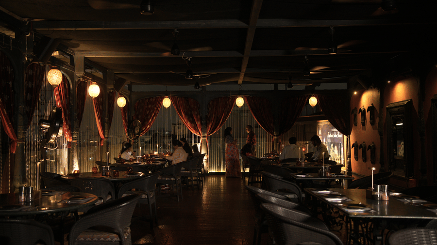 Infiniti Hotel, Indore | A dining space with lights, tables and chairs.