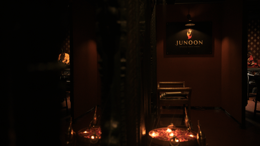 Infiniti Hotel, Indore | A dining space with a sign board, lights and chairs.