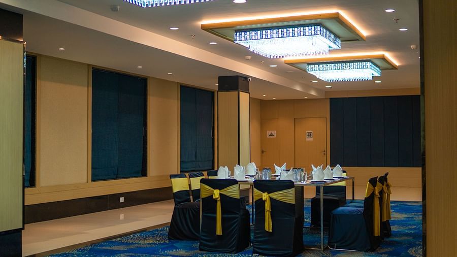 a hall with a table surrounded by decorated chairs and overhead lighting - Jardin Hotels