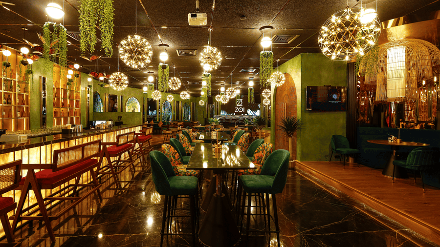 A wide view of a luxury lounge featuring a polished dark floor and stylish emerald green chairs - Jenneys Residency, Coimbatore