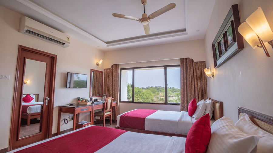 An interior view of a room showing the bed arrangement and scenic window view - Jenneys Residency, Coimbatore