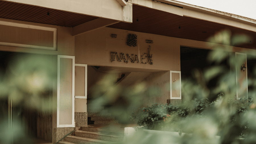An entrance area with steps leading up to a doorway, with signage above and plants partially covering the view in the foreground at Jivana Wellness Retreat, Bhopal.