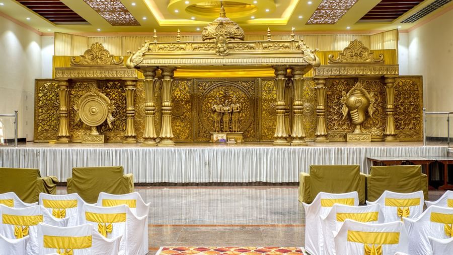 Decorated indoor wedding stage with golden backdrop and banquet seating at Kailash Conventions ECR.