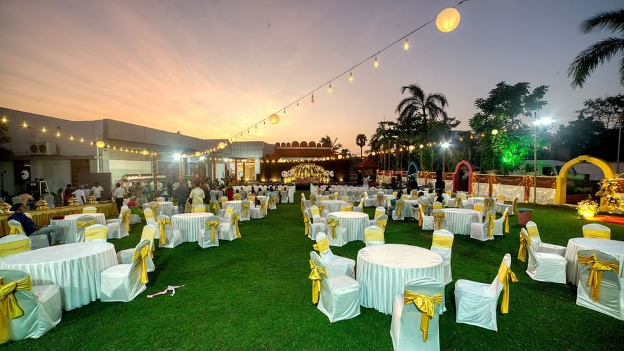 Outdoor event setup with banquet seating under decorative lights during dusk at Kailash Conventions ECR.