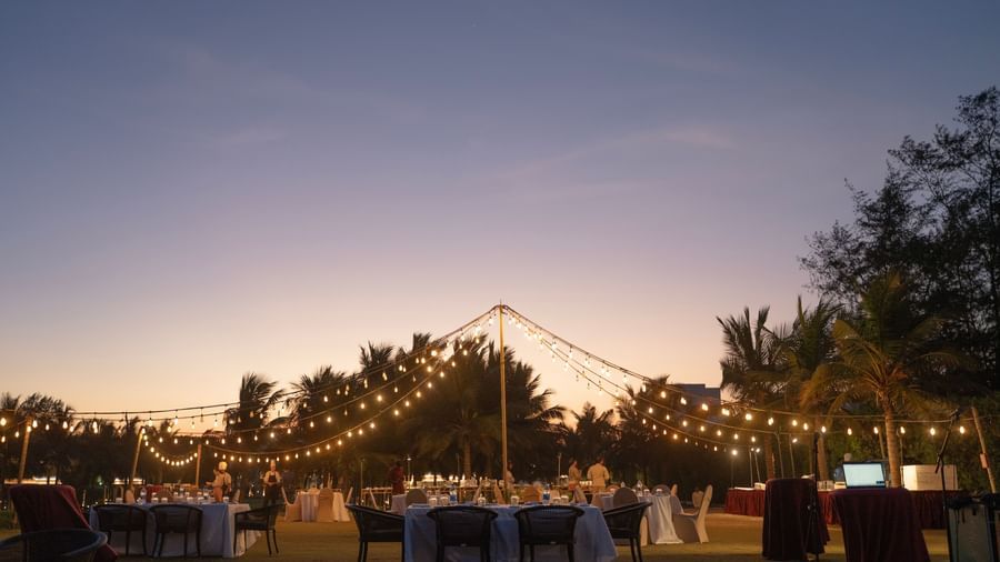 Outdoor evening event setup with string lights and a sunset backdrop - Kaldan Samudra Palace