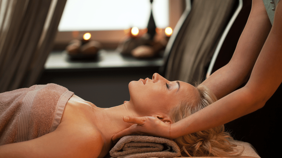 Woman receiving a head massage in a spa setting.