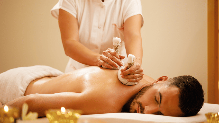 Woman using herbal pouches to massage a man's back.