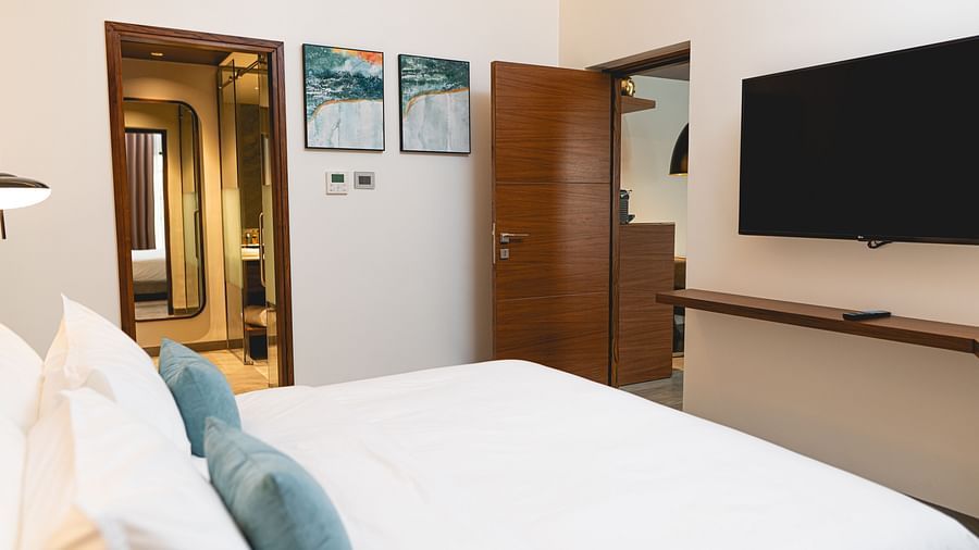 image of the bedroom with a wall mounted tv in the one bedroom suite of the kertel suites