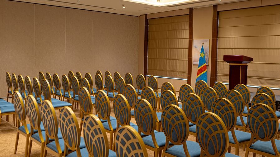 Rows of empty chairs at KertelSuites are arranged facing a podium in a well-lit conference room with beige walls and large windows covered by blinds