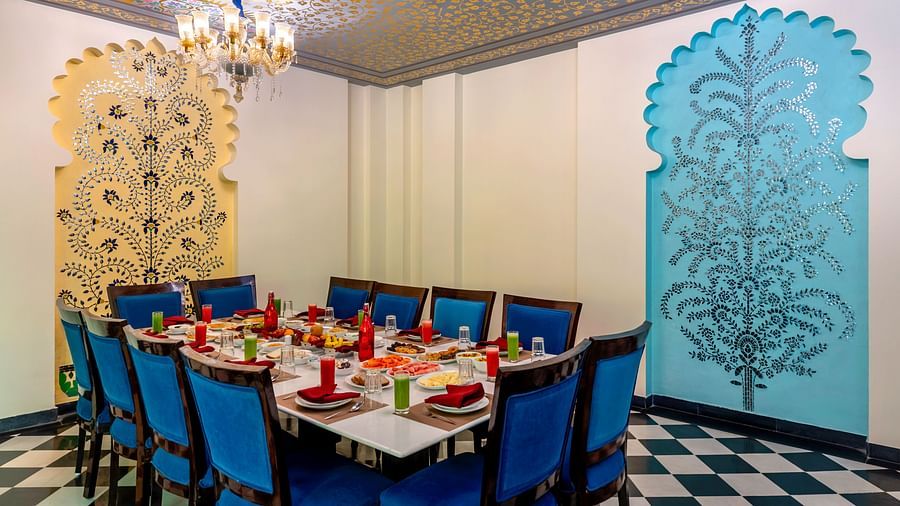 Elegant dining setup with blue chairs and Rajasthani wall motifs
