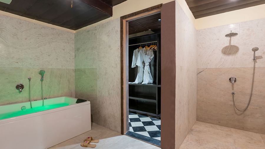 Luxurious bathroom with green bathtub, open closet, and rain shower at Kesar Bagh Palace.