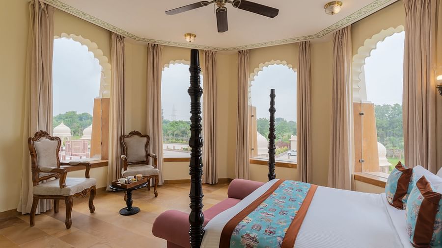 Elegant bedroom with arched windows overlooking scenic landscape at Kesar Bagh Palace.