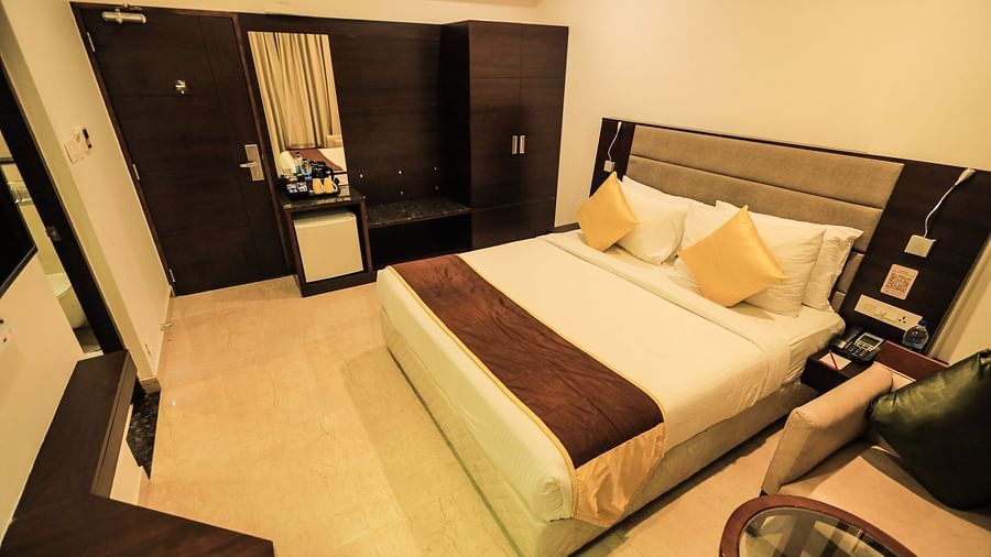 A spacious corner view room featuring a comfy bed and a functional working desk, perfect for relaxation and productivity.