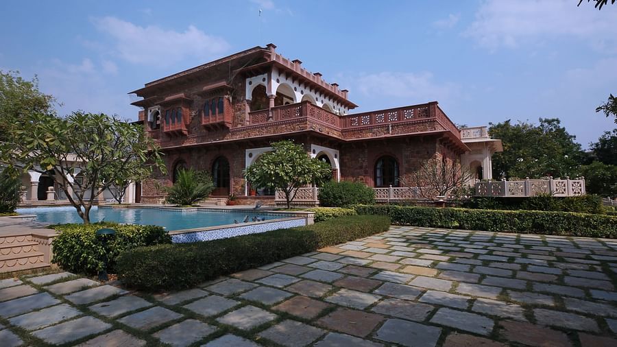 A majestic heritage palace with a cobblestone pathway, bushes and lush greenery in the backdrop - Khas Bagh, Jaipur.