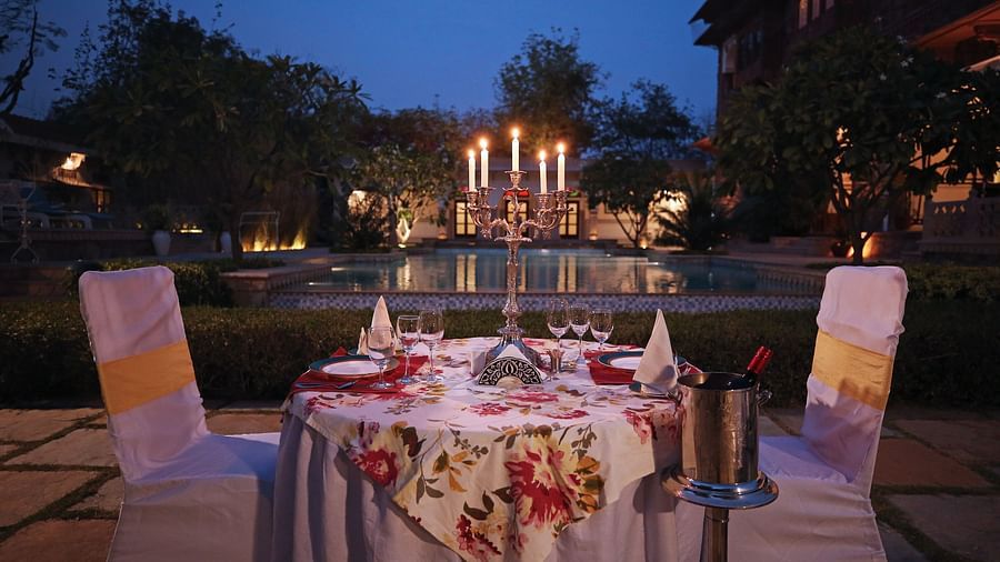  A table set for a romantic dinner by a swimming pool at dusk, illuminated by candles - Khas Bagh, Jaipur.