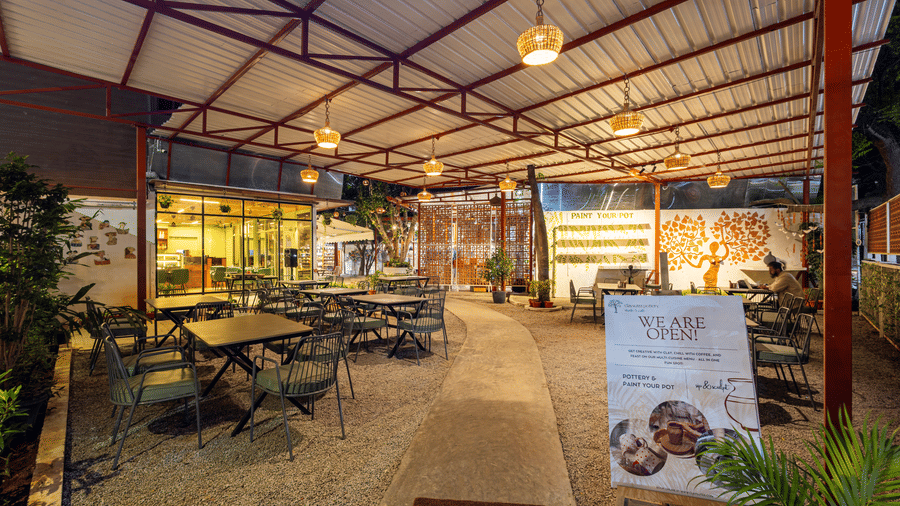 Claysutra Cafe & Restaurant at Kove Smart Stays seen during a darker time of the day, with ambient lighting, outdoor seating, and an overhead shed.