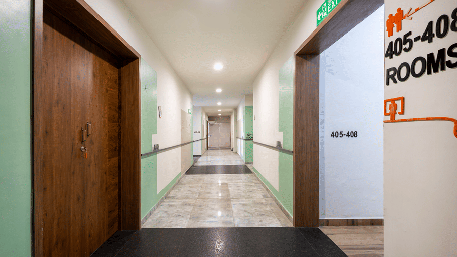 Well-lit corridor of Kove Smart Stays offering a view of multiple doorways to inner rooms & apartments.