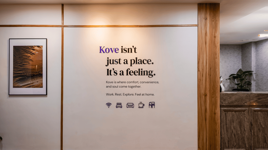Lobby of Kove Smart Stays featuring a wall with the writing 'Kove isn't just a place. It's a feeling.' seen under a spotlight, beside the reception desk of the hotel.