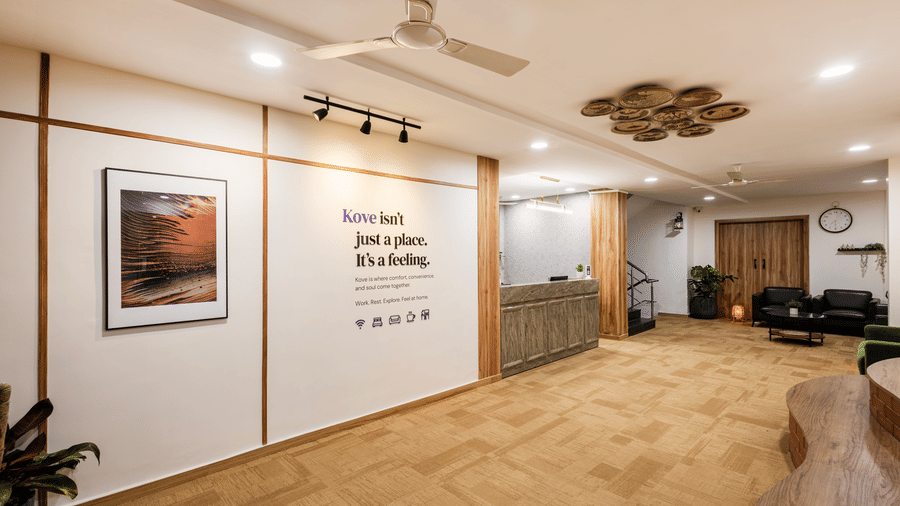 Lobby, entryway, and reception desk of Kove Smart Stays featuring wooden interiors, ample lighting, & signage of a quote on the wall.