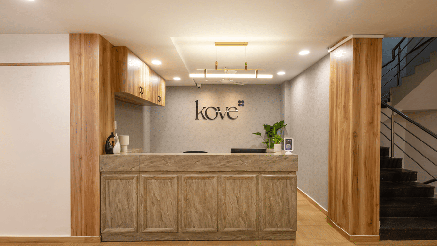 Close up of the reception desk of Kove Smart Stays, Hyderabad, seen with ample lighting, wooden flooring, and a desk made of wood.
