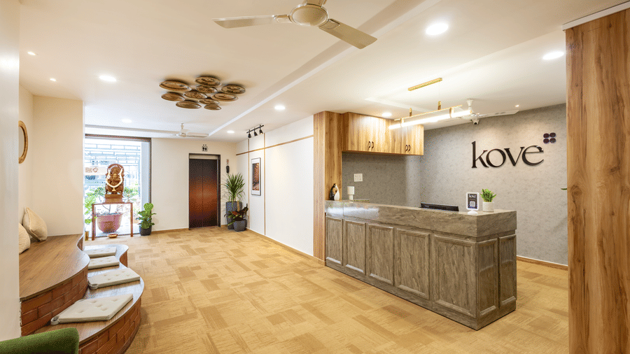 Wide view of Kove Smart Stays' lobby area and reception desk of Kove Smart Stays, showcasing the wooden flooring, ample overhead lighting & seating accommodations.