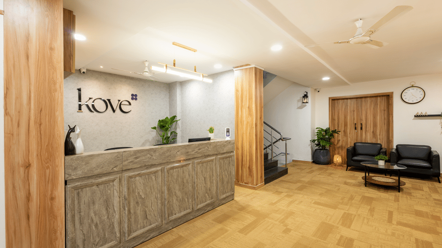 Diagonal view of the lobby and reception desk of Kove Smart Stays, with a focus on the word 'Kove' signage on the wall.