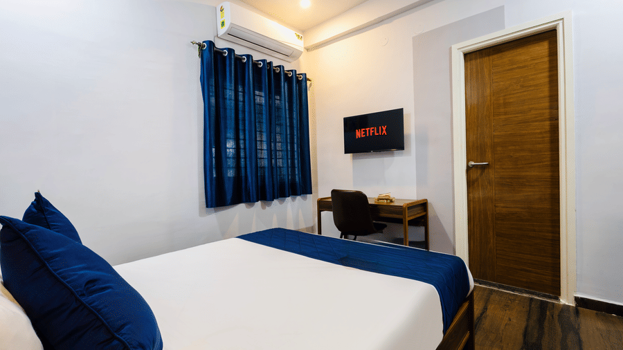 Bedroom of Studio Room featuring the queen size bed facing the wall-mounted TV and work desk.