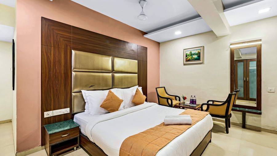 A well-lit executive room in Krushnai Resort featuring a double bed with white lnen and yellow runner.