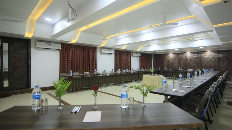 Meeting room at Krushnai Resort with tables and chairs arranged for a formal gathering, featuring  bottled water on tables.