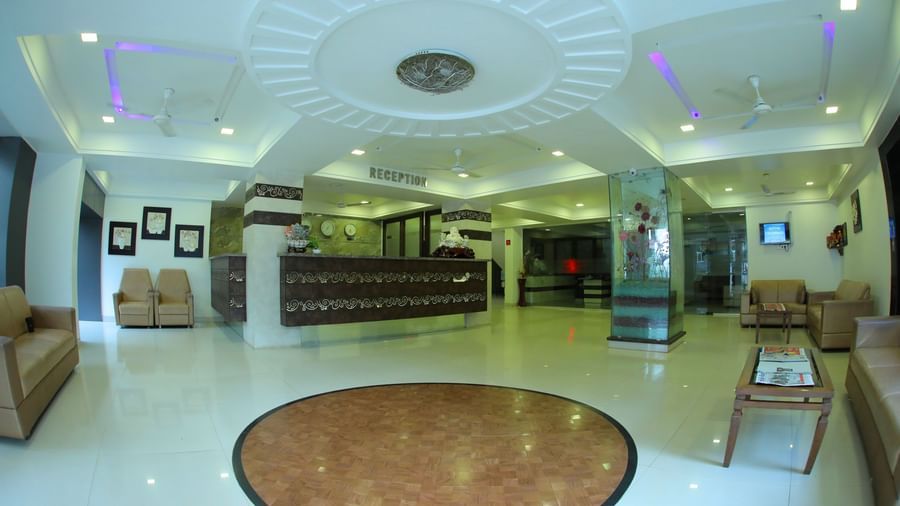 Krushnai Resort's bright lobby with a central mosaic, reception desk, and beige sofas under a decorative ceiling.
