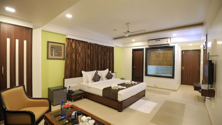 A wide view of a bedroom at Krushnai Resort, with a king size bed, seating area, and wall decor.