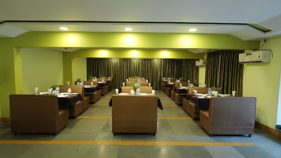 Wide view of the dining area at Krushnai Resort with several seating arrangements and yellow lighting.